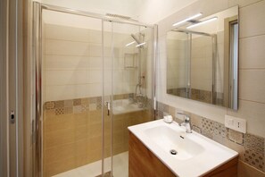 Une salle de bain moderne avec une douche à parois de verre, un lavabo blanc et un miroir au-dessus.