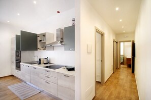 A modern kitchen with a built-in oven, microwave, and stove, a large island with a sink, and a stainless steel range hood.