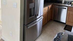 A kitchen with stainless steel appliances, wooden cabinets, and a tiled floor. - Escape to beautiful 4 BR home, Brightside OBX—Your Corolla Beach Retreat Awaits! (Corolla)