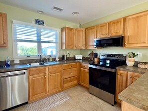 A kitchen with wooden cabinets, stainless steel appliances, a microwave, and a toaster. - Escape to beautiful Brightside OBX-Your Corolla Outer Banks Beach Retreat Awaits (Corolla)