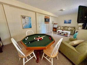 Ein Wohnzimmer mit Billardtisch, einer Couch und einem Fernseher.