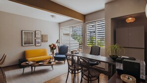 Una sala de estar moderna con un sofá amarillo, una mesa de comedor con sillas, una mesa de centro y una cocina con refrigerador y armarios.