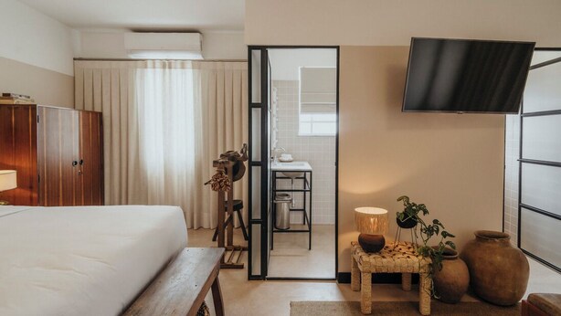 Habitación de hotel con cama, escritorio, televisión y vistas al baño.
