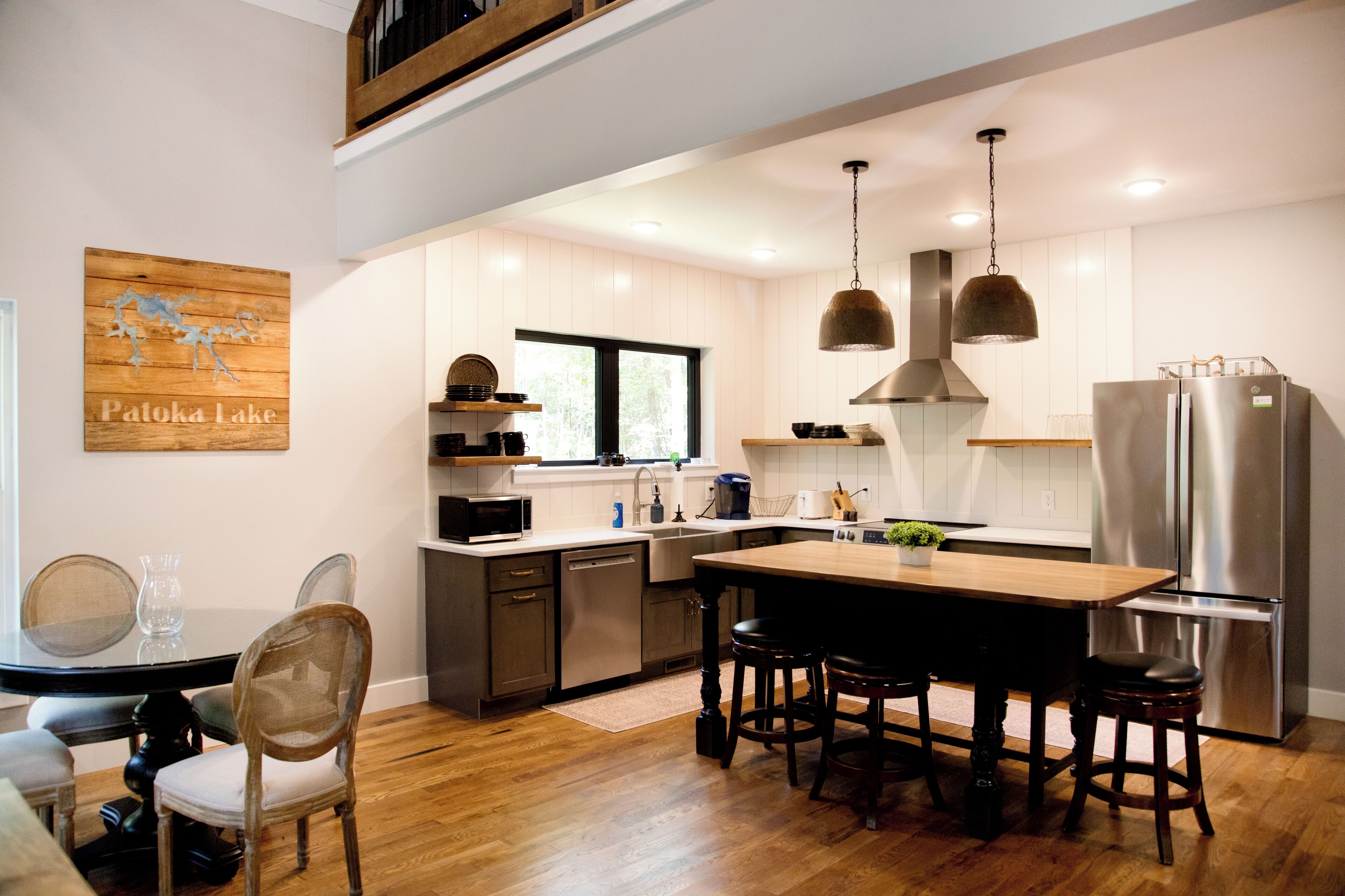 A modern kitchen with wooden flooring, stainless steel appliances, and a large island with bar stools.