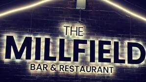 A sign for "The Millfield Bar & Restaurant" with a brick wall background and illuminated letters. - The millfield  (Broughton)