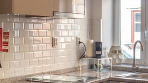 Et moderne køkken med hvide metrofliser, en stålvask og en kaffemaskine.