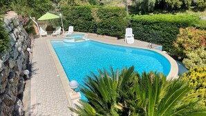 A rectangular swimming pool with a hot tub, surrounded by a stone wall and palm trees. - SEASIDE VILLA WITH POOL - PERFECT FOR FAMILY & FRIENDS (Saint-Raphaël)