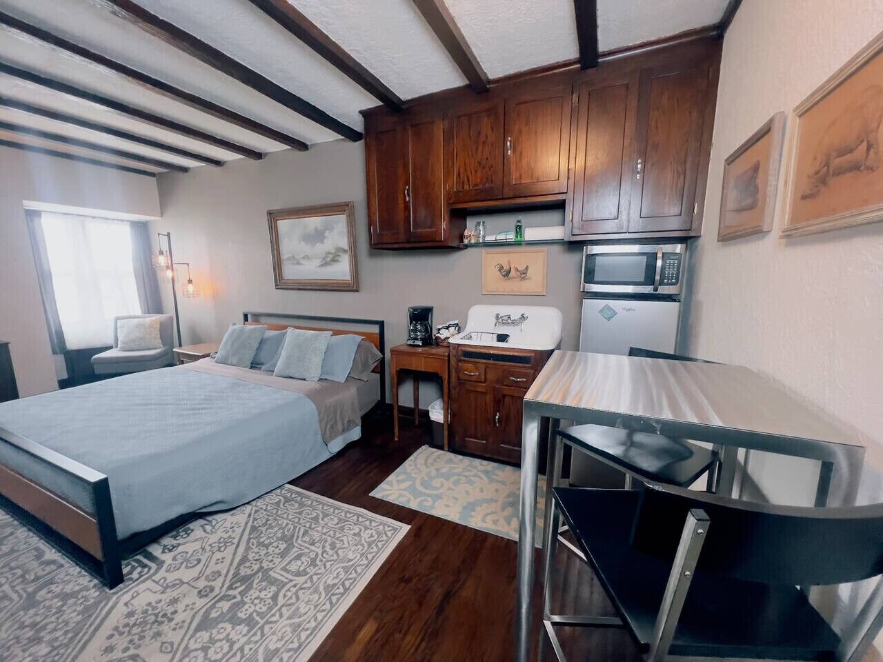 Una camera d'albergo compatta con un letto, una scrivania, un forno a microonde e un angolo cottura.