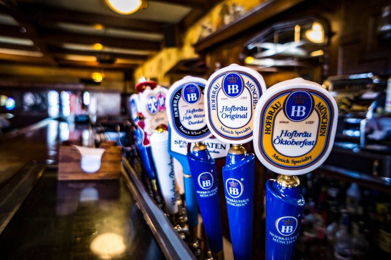 Un bar doté de plusieurs robinets à bière, chacun étant étiqueté avec les mentions « Hofbräu Original » et « Hofbräu Oktoberfest ».