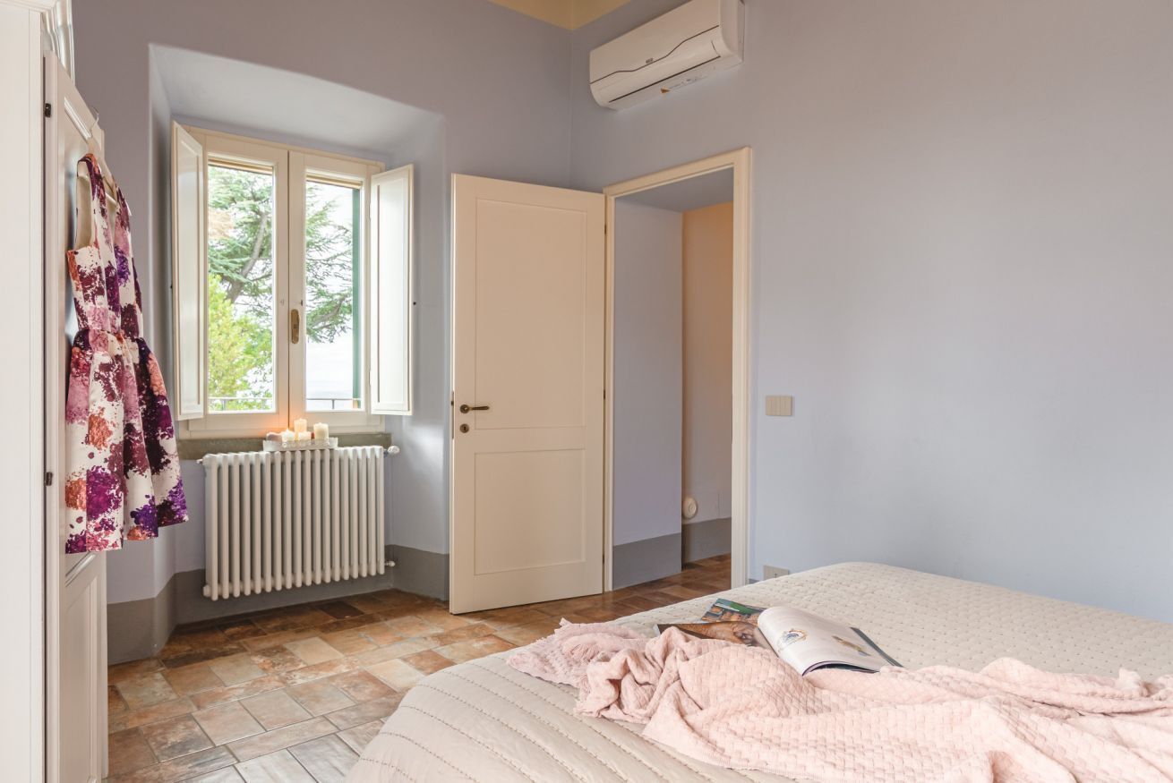 Une chambre à coucher avec un lit, un radiateur, une fenêtre et une porte.