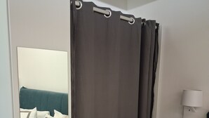 A bedroom with a bed, grey curtains, a bedside lamp, and a tiled floor. - House Sant Angelo (Acquapendente)