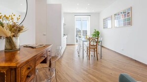 Un appartamento moderno con un tavolo da pranzo in legno, sedie trasparenti, un armadietto in legno e un'ampia finestra.