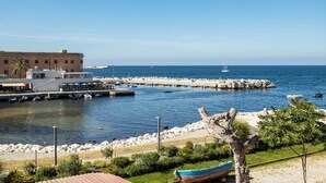 A coastal marina with boats, a building, and a rocky breakwater.
