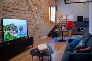 A living room with a television, a dining area, and a kitchen.