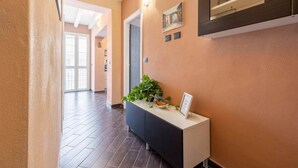A hallway with a reception desk, a potted plant, and a framed picture on the wall. - nonMama | 2-Bath Stylish Apt near Mondello Beach (Palermo)