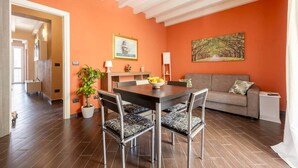 A dining area with a table and chairs, a sofa, a potted plant, and artwork on the walls. - nonMama | 2-Bath Stylish Apt near Mondello Beach (Palermo)