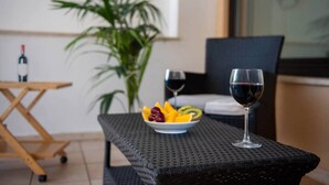 En matplats med ett bord av rotting, en skål med frukt och två vinglas.