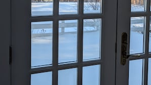 A white door with multiple windows, offering a view of a snowy landscape with trees and hills. - cozy home with mountain views. (Dorset)