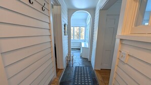 A narrow hallway with white siding, a blue patterned rug, and a radiator. - cozy home with mountain views. (Dorset)