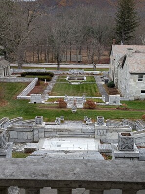 Een kerkhof met stenen grafstenen en een centraal monument, omgeven door stenen muren en een gazon.