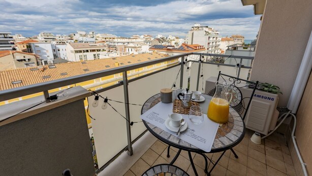 Un balcon avec une table préparée pour le petit-déjeuner, un climatiseur Samsung et une vue sur la ville.