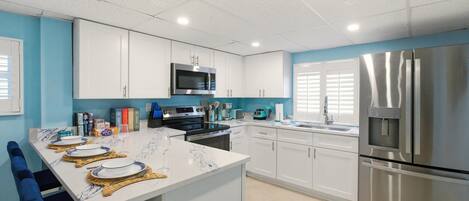 Una cocina moderna con armarios blancos, electrodomésticos de acero inoxidable y encimera de mármol.