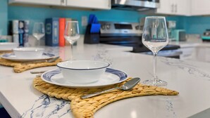 Una encimera de cocina con un bol blanco y dos copas de vino sobre individuales tejidos.