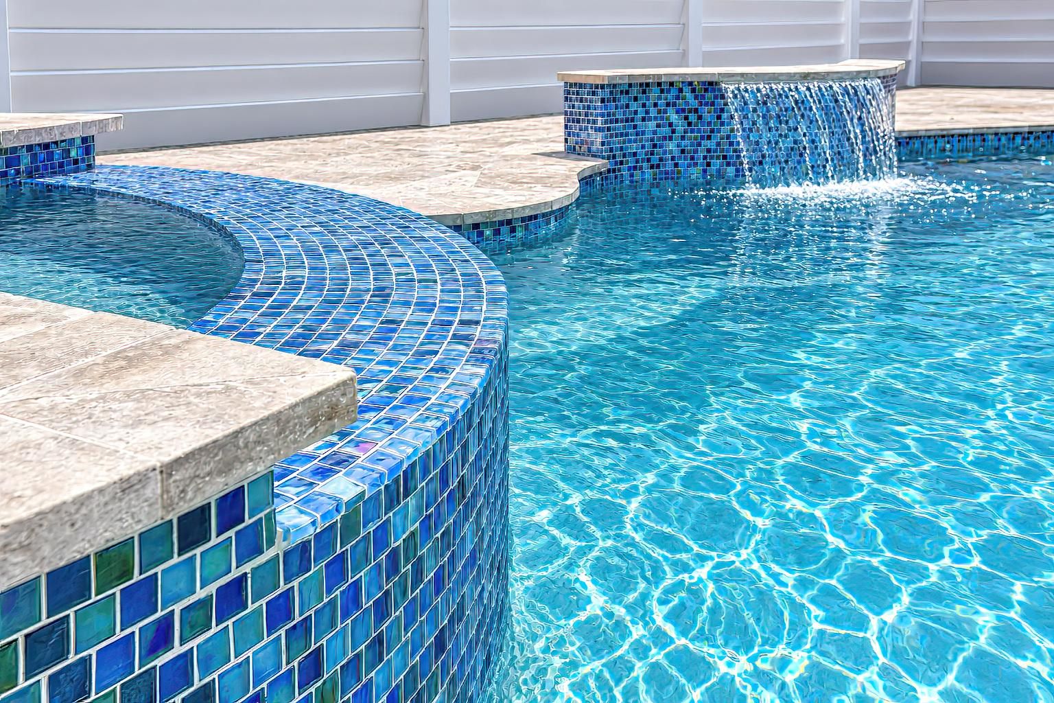 Piscina com azulejos de mosaico azul e borda de pedra.