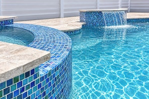 A swimming pool with blue mosaic tiles and a stone edge. - Sand Dollar Suite (Fort Myers Beach)
