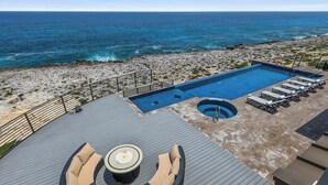 Une piscine sur le toit offrant une vue sur l’océan, un espace salon circulaire et un jacuzzi.