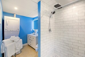 Une salle de bain moderne équipée d’une douche, d’un lave-linge et d’un lavabo.