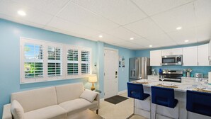 A compact kitchen with white cabinets, a microwave, and a refrigerator. - Coral Suite (Fort Myers Beach)