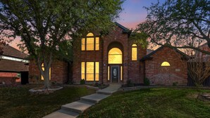 A brick house with a central arched entrance, large windows, and a well-maintained lawn. - Luxury Backyard Pool & Patio Oasis (4-BD/2.5-BA) (Lewisville)