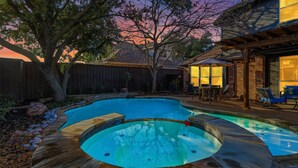 A backyard with a swimming pool, a wooden deck, and a patio area with outdoor furniture. - Luxury Backyard Pool & Patio Oasis (4-BD/2.5-BA) (Lewisville)