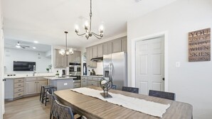 A modern kitchen with a central island, stainless steel appliances, and a chandelier. - Luxury Backyard Pool & Patio Oasis (4-BD/2.5-BA) (Lewisville)