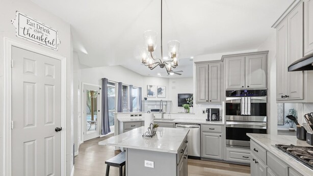 A modern kitchen with white cabinetry, stainless steel appliances, and a central island. - Luxury Backyard Pool & Patio Oasis (4-BD/2.5-BA) (Lewisville)