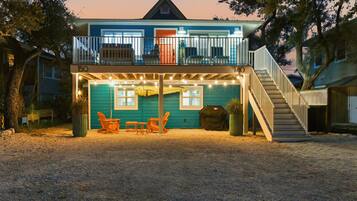 A two-story house with a covered patio area, a staircase, and outdoor seating.