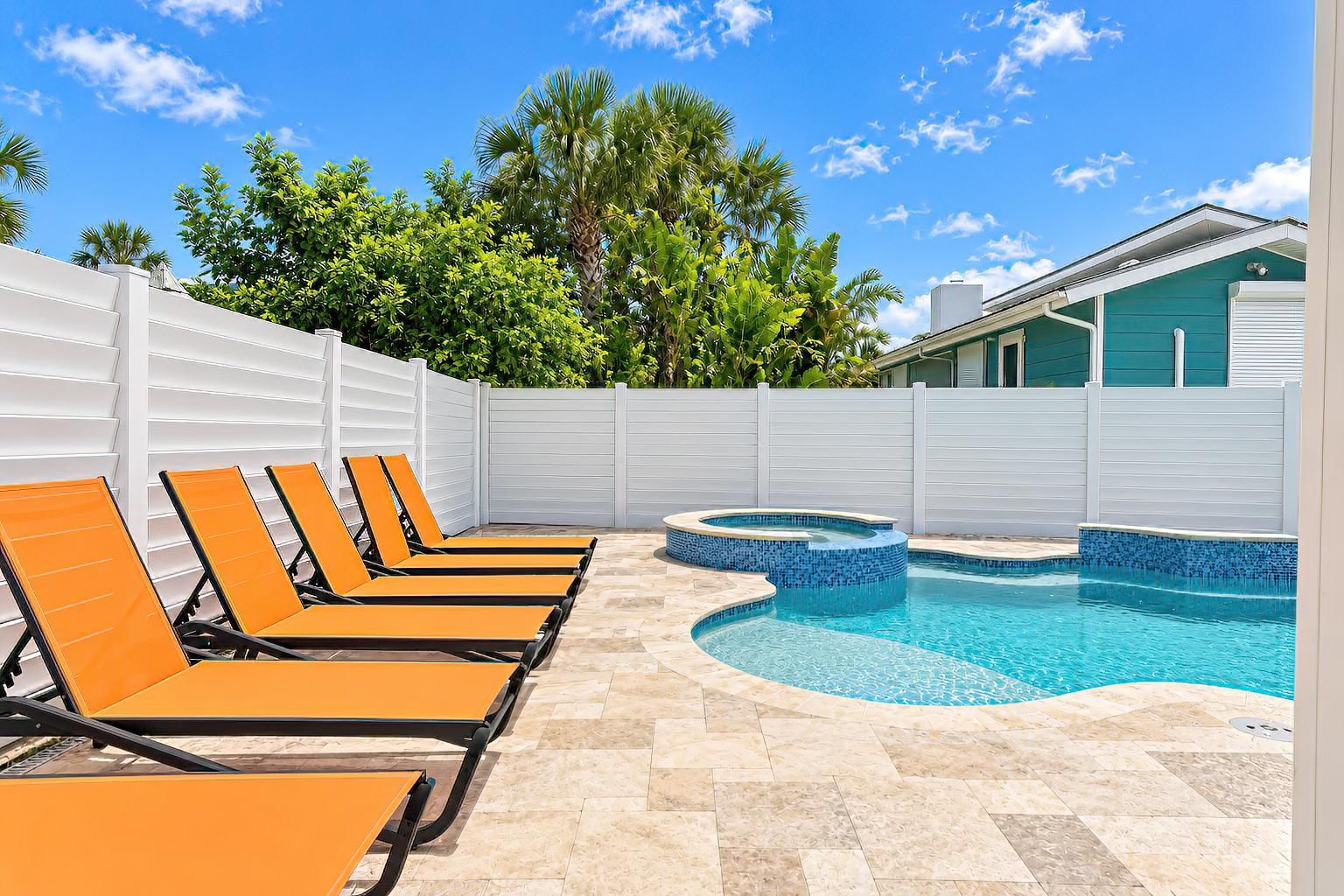 A pool area with lounge chairs and a hot tub.