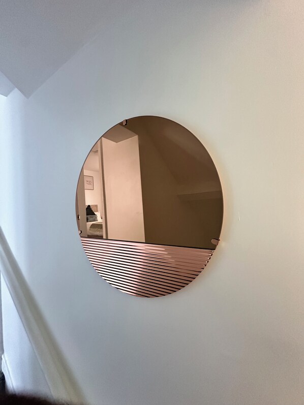 Ein runder Spiegel mit Metallrahmen an einer weißen Wand.