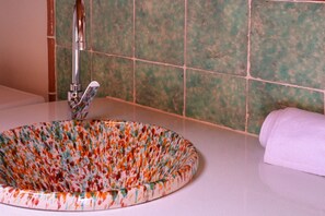Un baño con un lavabo redondo, un grifo y una toalla a la derecha.