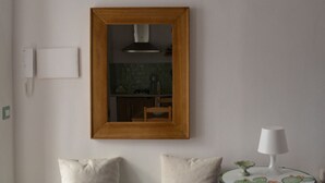 A room with a wooden-framed mirror, a small round table with a lamp, and two pillows. - Salvia is an independent loft located on the ground floor, featuring a small private courtyard furnished with chairs and a table. The space consists of an open-plan area with a sofa bed and equipped kitchen, as well as a spacious bathroom with a shower.  (Santo Stefano di Camastra)