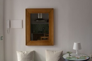 Ein Zimmer mit einem spiegelnden Holzbettrahmen, einem kleinen runden Tisch mit einer Lampe und zwei Kissen.