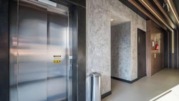 A modern elevator with a metallic finish and a wheelchair accessibility sign.
