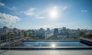 Een terras op het dak met een helder uitzicht op een stadsbeeld, inclusief gebouwen en een verafgelegen berg.