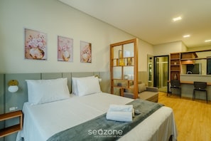 Une chambre d’hôtel avec un lit, un bureau, une chaise, un miroir et des œuvres d’art accrochées au mur.