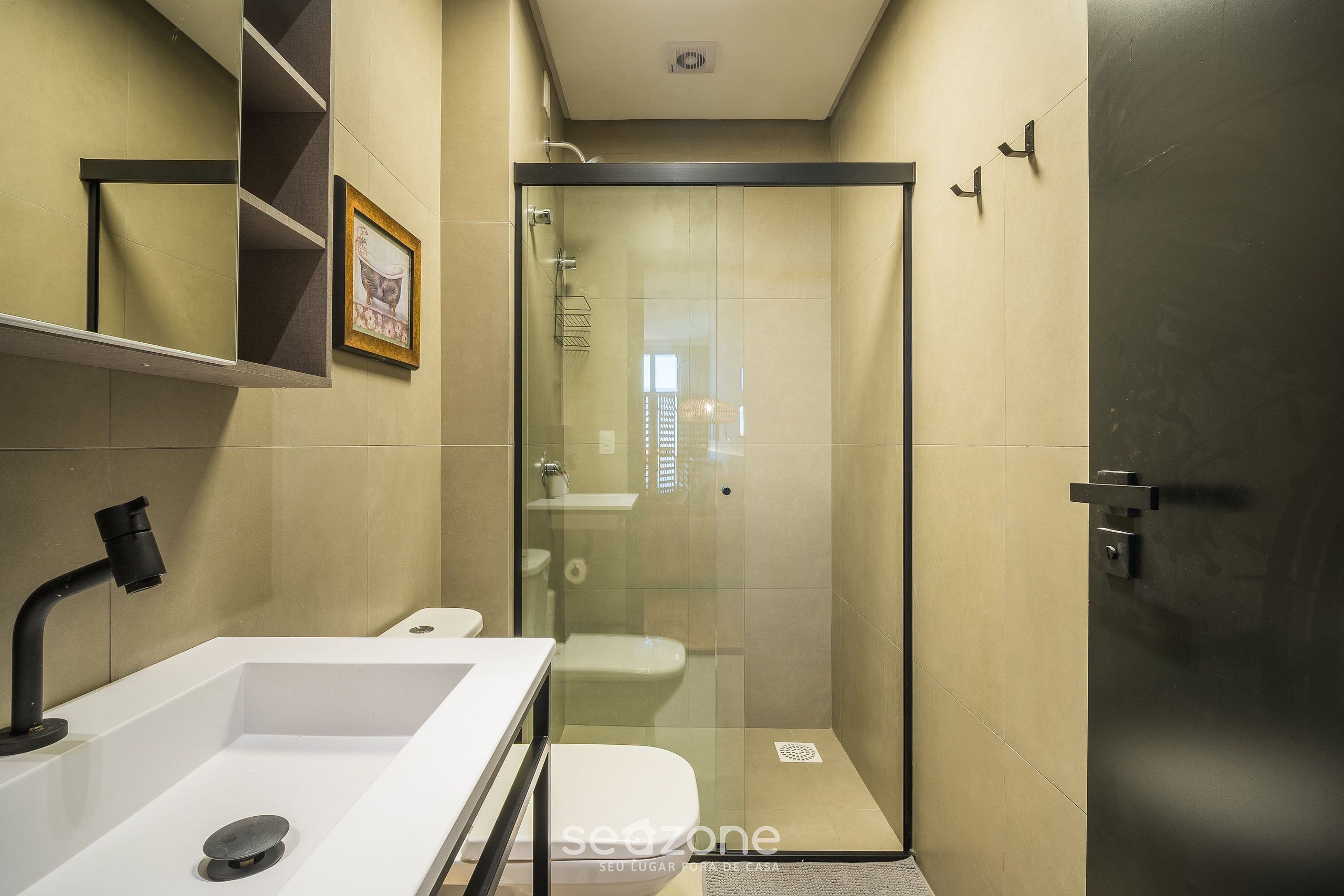 A modern bathroom with a glass-enclosed shower, a white sink, and a toilet.