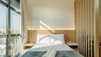 A modern bedroom with a large bed, a view of the city, and a wooden partition.