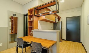 Une petite cuisine équipée avec un plan de travail en bois, deux chaises et une étagère intégrée.
