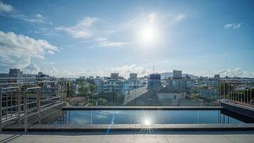 A rooftop terrace with a clear view of a cityscape, including buildings and a distant mountain.