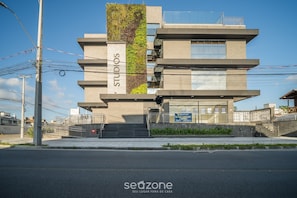 A multi-story building with a vertical garden on the facade, a sign reading 'STUDIOS,' and a staircase leading to the entrance. - Complete Stay Just 550 Meters From Praia dos Ingleses - Ldus (Florianópolis)